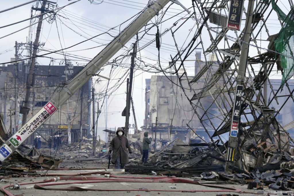 Individuals navigate a charred marketplace, ravaged by fire following the earthquake, in Wajima within Japan's Ishikawa prefecture.