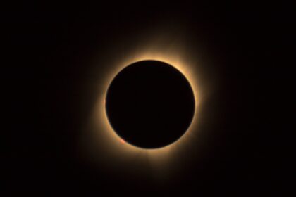 Photograph of a rare hybrid solar eclipse, showcasing the moon partially covering the sun, casting a shadow on Earth, with a radiant corona visible around the moon's silhouette.